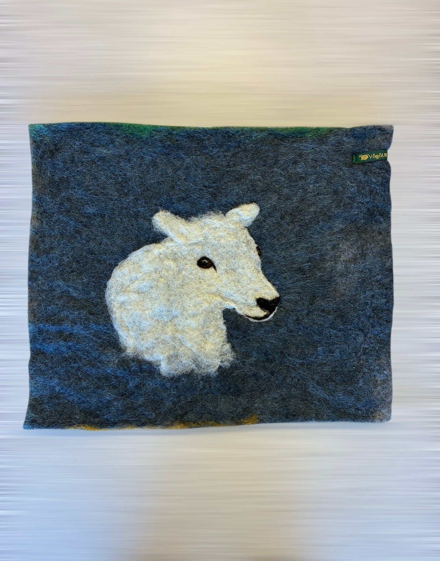 Sitteunderlag med nålefilta sauehodet og håndfarga ull som bakgrunn